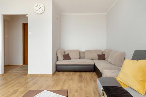 Una sala de estar con un sofá y un reloj en la pared. en Komfortowe Studio w Gdańsku dla czterech osób by Noclegi Renters, en Gdansk