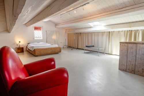 フェラーラにあるBabette Roomのベッドと赤い椅子のある寝室