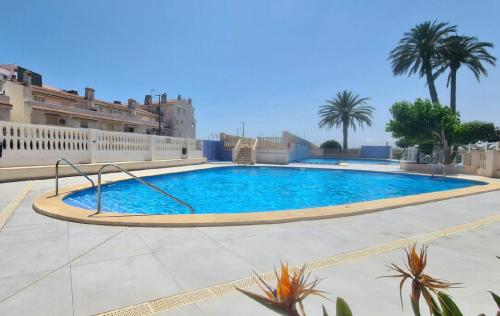 ein großer Swimmingpool in einem Innenhof mit Palmen in der Unterkunft Vista Mar Apartamento Playa Farnals in Playa Pobla de Farnals