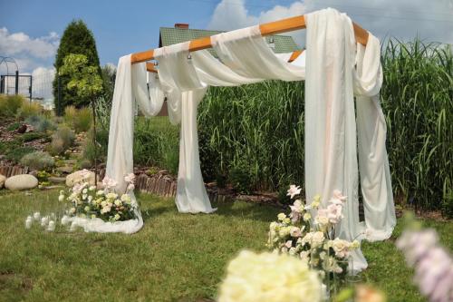 an arch with white curtains and flowers on the grass at Czereśniowe Wzgórze Sandomierz jakuzzi in Sandomierz