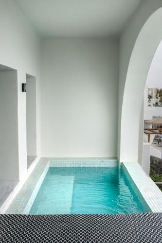 a swimming pool in a white room with blue water at Kudos Suites Firostefani in Fira