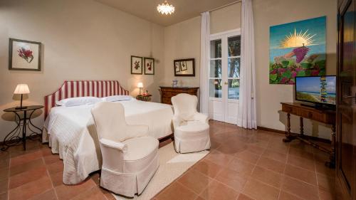 a bedroom with a bed and two chairs and a television at Principi di Butera 14, Emma Villas in Butera