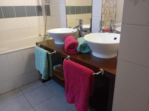 ein Badezimmer mit einem Waschbecken, einer Badewanne und Handtüchern in der Unterkunft La longue vue in Les Avirons
