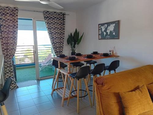eine Küche mit einer Bar mit Hockern und einem Tisch in der Unterkunft La longue vue in Les Avirons