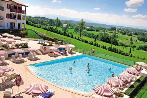 a pool at a resort with chairs and umbrellas at T1 Bis avec piscine vue golf et montagnes in Arcangues