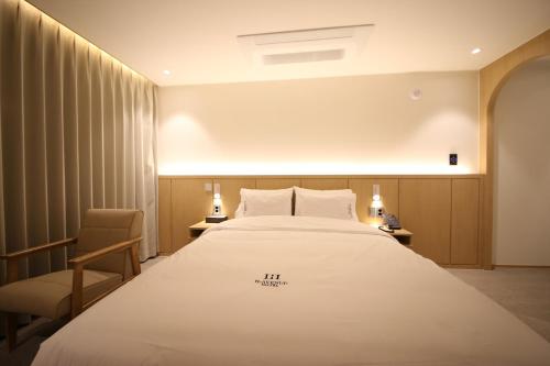 a hotel room with a large bed and a chair at H avenue Hotel Jeonju Deokjin in Jeonju