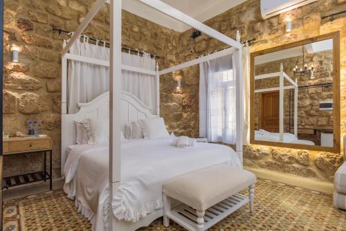 a bedroom with a white bed and a mirror at Lebanese Diaspora Village in Batroûn