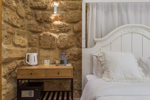 a bedroom with a white bed and a stone wall at Lebanese Diaspora Village in Batroûn