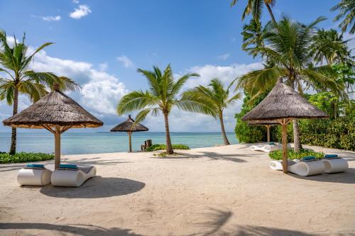 a beach with umbrellas and palm trees and the ocean at Ycona Eco-Luxury Resort, Zanzibar in Dikoni