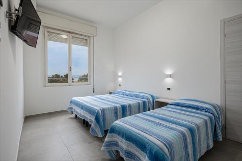 two beds in a room with a window at Hotel Flora in Cesenatico