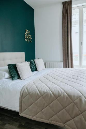 - une chambre avec un grand lit blanc aux murs verts dans l'établissement DOMITYS - Marguerite, à Bourg-en-Bresse