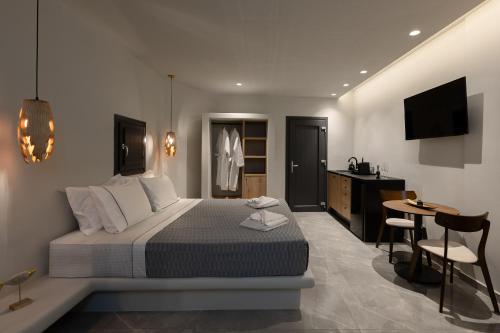 a bedroom with a bed and a desk and a television at Kudos Suites Firostefani in Fira