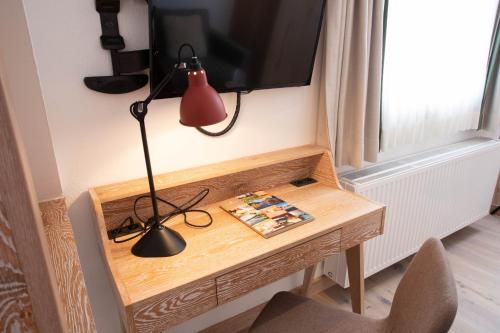 a desk with a lamp and a television on a wall at Hotel Hochschober in Turracher Hohe