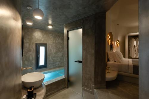 a bathroom with a sink and a toilet and a bed at Kudos Suites Firostefani in Fira