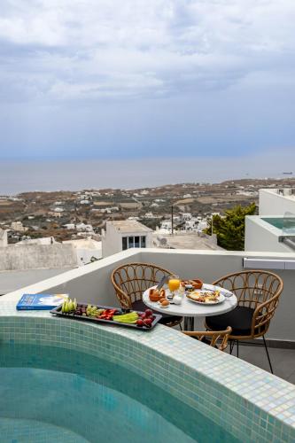 a table with food on it next to a swimming pool at Kudos Suites Firostefani in Fira