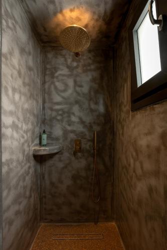 a bathroom with a shower with a sink and a window at Kudos Suites Firostefani in Fira