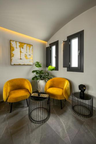 two yellow chairs and a table in a room at Kudos Suites Firostefani in Fira