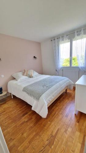 a white bedroom with a bed and a wooden floor at Le gîte de la Sienne in Regnéville-sur-Mer
