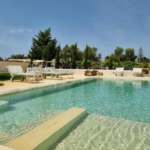 a swimming pool with chaise lounges and chairs at Villa Dei Lidi - HomeSalento com in Torre San Giovanni Ugento