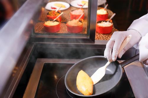 una persona está cocinando comida en una sartén en Sheraton Miyako Hotel Osaka, en Osaka