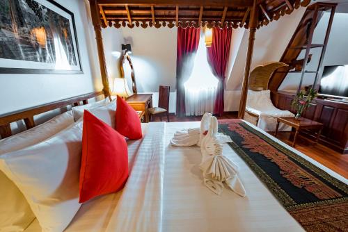 a bedroom with a large bed with red pillows at The Suite By Royal Crown Hotel in Siem Reap