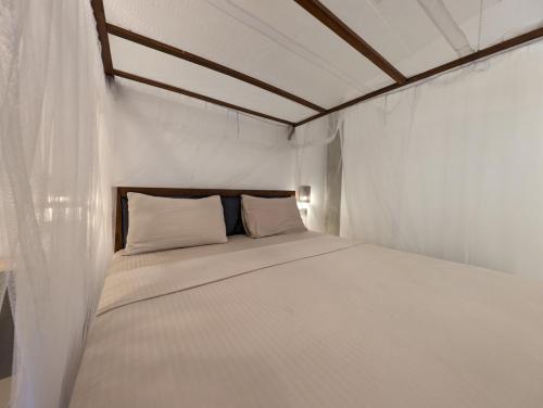 a white bed in a white room with a wooden ceiling at Beach View in Arugam Bay