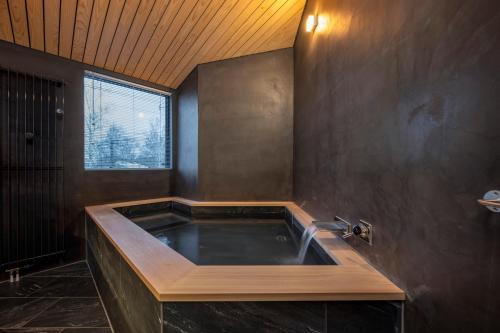 Una bañera grande en un baño con ventana. en Foxwood F, en Niseko