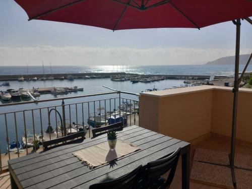a table with an umbrella on a balcony with a harbor at La Perla del Mare in Pisciotta