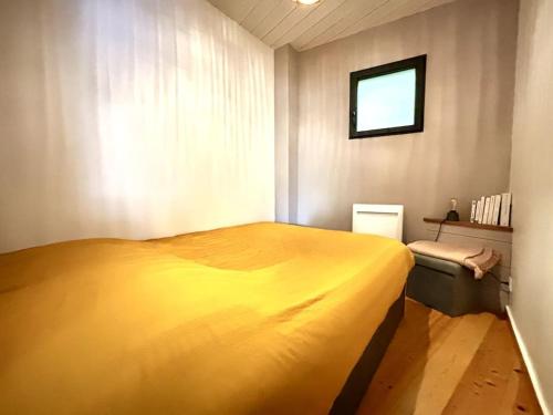 - une chambre avec un grand lit jaune et une fenêtre dans l'établissement Appartement intimiste proche de la mer, à Arcachon