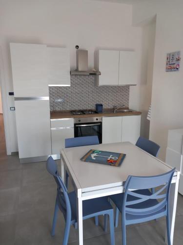 a kitchen with a white table and blue chairs at La Perla del Mare in Pisciotta