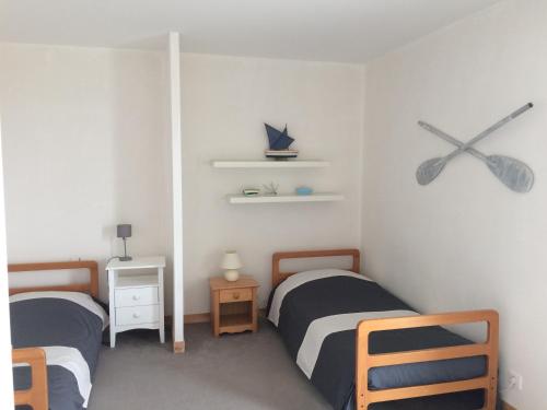 a bedroom with two beds and a clock on the wall at Maison les Courlis - belle vue mer in Plozévet