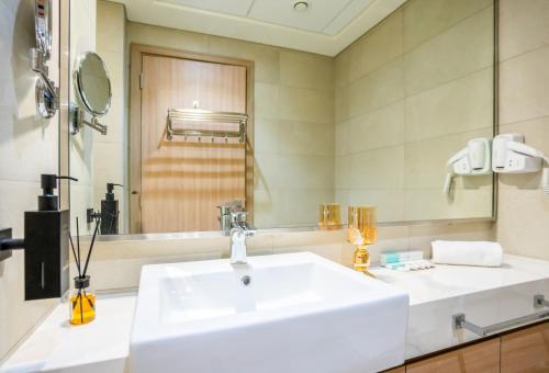 une salle de bains avec un lavabo blanc et un miroir dans l'établissement Zapbed House - AZIZI RIVIERA, à Dubaï