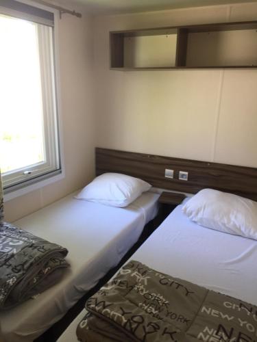 deux lits dans une petite pièce avec une fenêtre dans l'établissement Mobil-home de charme avec deux terrasses, à Vias
