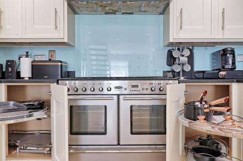 a kitchen with white cabinets and stainless steel appliances at LMV Property - Modern Luxury Family Home in Theydon Bois With London Skyline Views in Theydon Bois