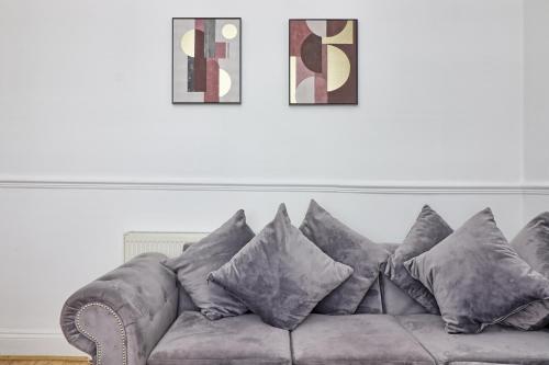 a grey couch with pillows in a living room at LMV Property - Modern Luxury Family Home in Theydon Bois With London Skyline Views in Theydon Bois