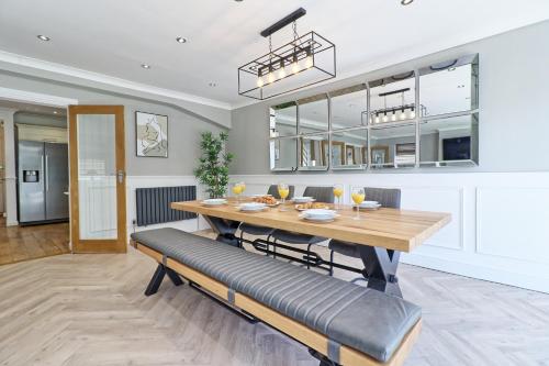 a dining room with a wooden table and benches at LMV Property - Modern Luxury Family Home in Theydon Bois With London Skyline Views in Theydon Bois