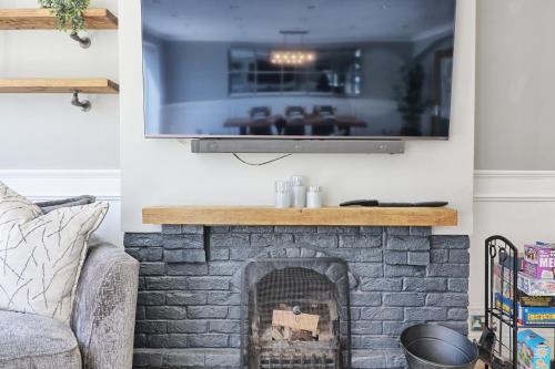 a living room with a fireplace with a flat screen tv at LMV Property - Modern Luxury Family Home in Theydon Bois With London Skyline Views in Theydon Bois