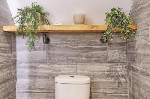 a bathroom with a toilet and some plants on a wall at LMV Property - Modern Luxury Family Home in Theydon Bois With London Skyline Views in Theydon Bois