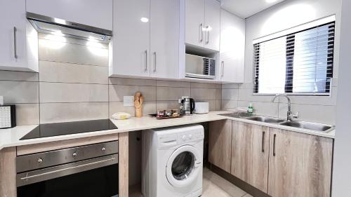a kitchen with a washing machine and a sink at La Bella Vita Bellamare in Summerstrand