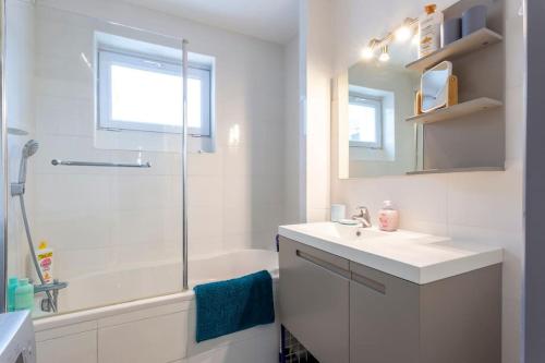 une salle de bain blanche avec un lavabo et une douche dans l'établissement Chez Laurence - Élégant appartement climatisé avec wifi et parking, à La Grande Motte