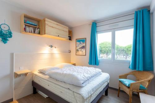 - une chambre avec un lit doté de rideaux bleus et d'une fenêtre dans l'établissement Chez Laurence - Élégant appartement climatisé avec wifi et parking, à La Grande Motte