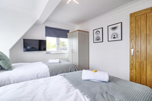 a bedroom with two beds and a window at LMV Property - Modern Luxury Family Home in Theydon Bois With London Skyline Views in Theydon Bois