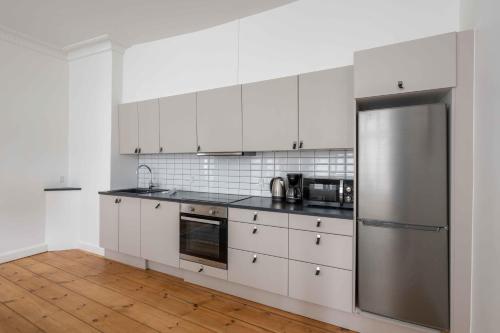 a kitchen with white cabinets and a stainless steel refrigerator at Charming apartment in latin quarter of Copenhagen in Copenhagen