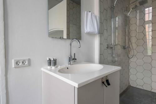 a white bathroom with a sink and a shower at Charming apartment in latin quarter of Copenhagen in Copenhagen
