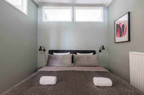 a bedroom with a bed with two pillows and two windows at Charming apartment in latin quarter of Copenhagen in Copenhagen