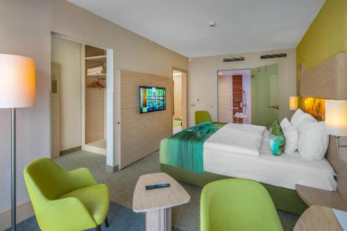 a hotel room with a large bed and chairs at Lifestyle Hotel Mátra in Mátraháza