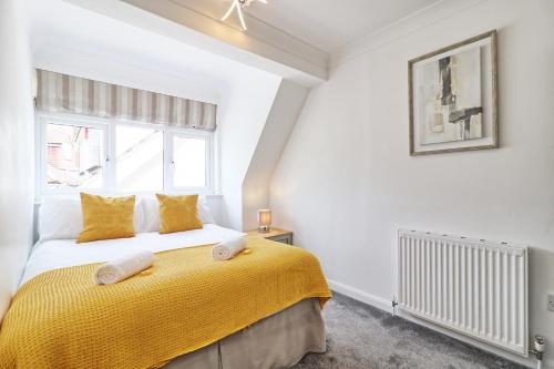 a bedroom with a bed with yellow sheets and a window at LMV Property - Modern Luxury Family Home in Theydon Bois With London Skyline Views in Theydon Bois