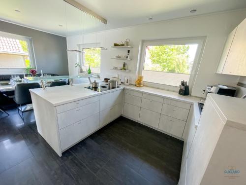 a kitchen with white cabinets and a sink and a window at Ferienhaus Lindenweg Bad Bederkesa in Bad Bederkesa