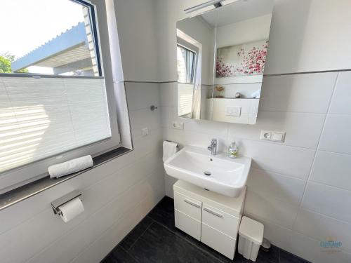 a white bathroom with a sink and a window at Ferienhaus Lindenweg Bad Bederkesa in Bad Bederkesa