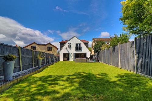 a yard with a fence and a house at LMV Property - Modern Luxury Family Home in Theydon Bois With London Skyline Views in Theydon Bois